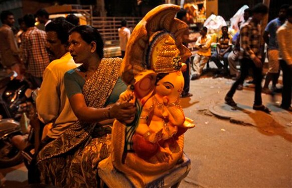 हैदराबाद में भगवान गणेश की प्रतिमा पूजा के लिए ले जाते श्रद्धालु।