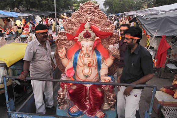 अहमदाबाद में भगवान गणेश की प्रतिमा को पूजा के लिए ले जाते श्रद्धालु।