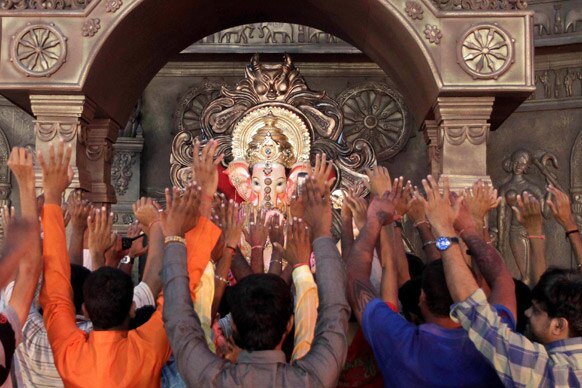 मुंबई में गणेश चतुर्थी के त्योहार के दौरान श्रद्धालु हाथ उठाकर गणपति की पूजा करते हुए।