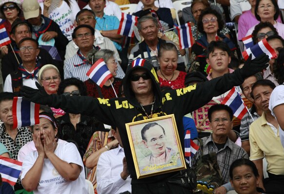 बैंकॉक में थाई प्रदर्शनकारी गले में राज भूमिबोल अद्युदेज की तस्वीर लटकाकर प्रदर्शन करते हुए।
