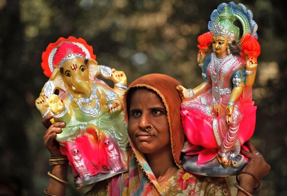 दीपावली के मौके पर इलाहाबाद में गणेश-लक्ष्मी की मूर्ति बेचने के लिए जे जाती एक महिला।