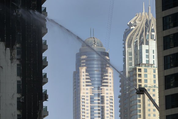दुबई की एक इमारत में लगी आग को बुझाते अग्निशमनकर्मी।