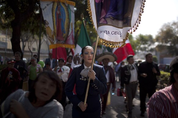 मेक्सिको सिटी में संत कसिला की तस्वीर के साथ प्रदर्शन करते लोग।