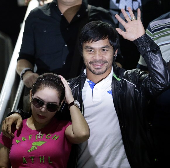 मनीला में फिलीपीन्स के बॉक्सर मन्नी पक्वीओ अपनी पत्नी के साथ हाथ हिलाकर लोगों का अभिवादन स्वीकार करते हुए।