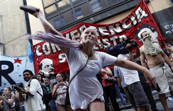 अर्जेंटीना में एक गायब युवा महिला के समर्थन में विरोध प्रदर्शन के दौरान पुलिस पर पत्‍थर फेंकते हुए प्रदर्शनकारी।