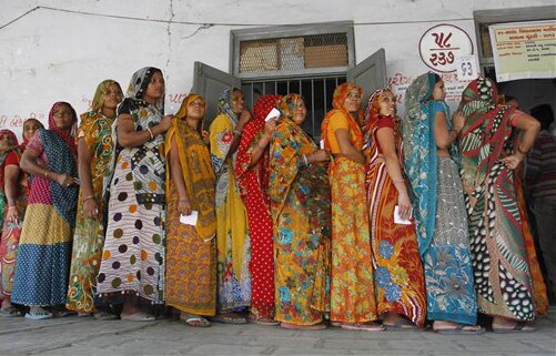 गुजरात: पहले चरण की वोटिंग के दौरान अहमदाबाद जिले के साणंद स्थित एक पोलिंग बूथ पर वोट डालने के लिए अपनी बारी का इंतजार करतीं कतारबद्ध महिलाएं।