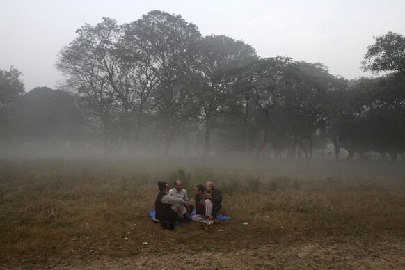कोलकाता में सुबह के वक्त एक खेत में बैठे लोग।