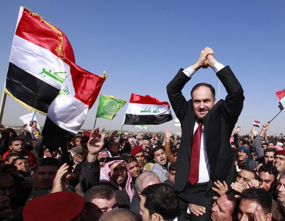 इराक के बगदार में एक प्रदर्शन के दौरान वित्‍त मंत्री राफिया अल इसावी को कंधे में उठाए हुए समर्थक।
