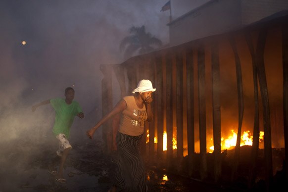 हैती में पोर्ट मार्केट में फैले आग के सामने से अपने मुंह और नाक को ढककर गुजरती हुई एक महिला।