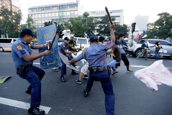 फिलीपींस की राजधानी मनीला में अमेरिकी दूतावास की मुहर पेंट कर प्रदर्शन करते प्रदर्शनकारियों को खदेड़ती पुलिस।