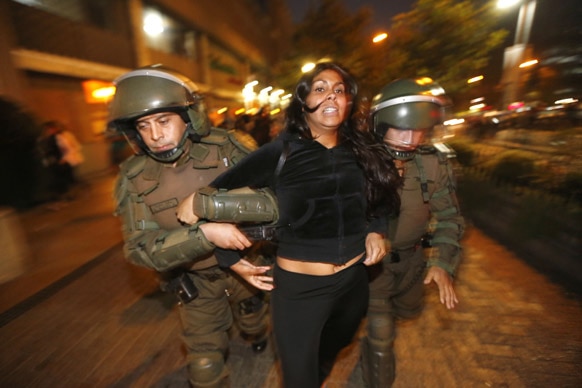 चिली के सेंटियागो में मपूची इंडियंस के समर्थन में प्रदर्शन करते प्रदर्शनकारी महिला को गिरफ्तार करती पुलिस। ये मपूची सरकार से जमीन लौटाने की मांग कर रहे हैं।