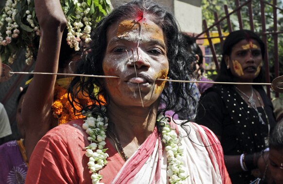 कोलकाता से 55 किमी. दूर बंडेल में एक धार्मिक समारोह में लोहे की छड़ को अपने गालों में घुसाकर भक्ति भाव दर्शाती एक महिला श्रद्धालु।