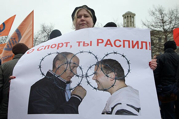 मास्को में विपक्ष की रैली में प्रधानमंत्री दमित्रि मेदेवेदेव एवं राष्ट्रपति व्लादिमीर पुतिन के पोस्टर के साथ प्रदर्शन करता एक व्यक्ति।