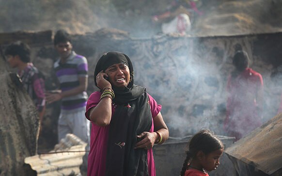 नई दिल्ली में घर में आग लगने से सबकुछ स्वाहा होने से रोती महिला।