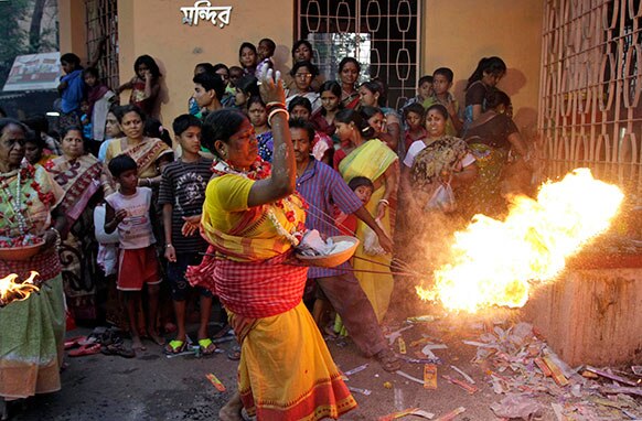 कोलकाता में शिव गजन हिंदू पर्व के दौरान भक्त शिव भगवान के मंदिर के सामने आग से पूजा का करते हुए।