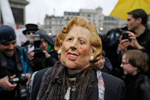 लंदन में ब्रिटेन के पूर्व प्रधानमंत्री मार्गेट थैचर का मास्क पहने प्रदर्शनकारी।