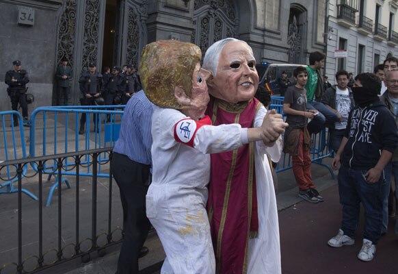 स्पेन में मास्क पहनकर विरोध-प्रदर्शन करते लोग।