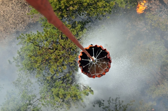 कोलो में जंगल की आग को बुझाने के लिए हेलीकॉप्टर से पानी का छिड़काव किया जा रहा है।