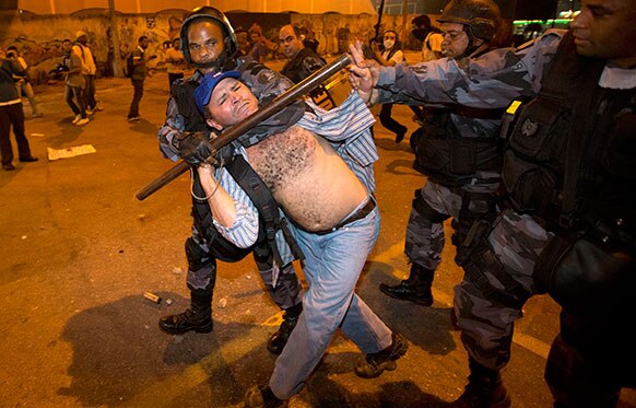 रियो डी जेनेरो में एक प्रदर्शनकारी को काबू में करती पुलिस।