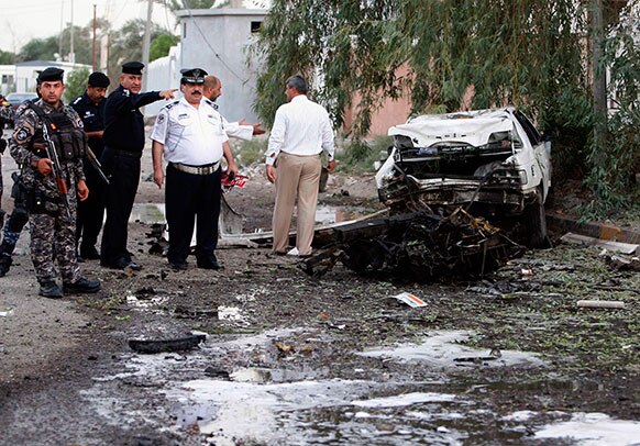 बगदाद से 550 किलोमीटर दूर बसरा में कार बम हमलों की जांच करते सुरक्षाकर्मी।