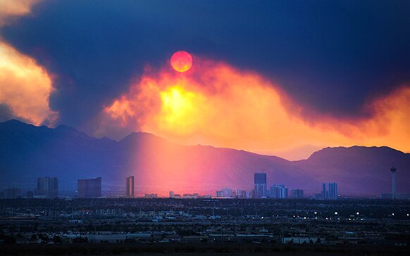 लास वेगास में सूरज के आसपास माउंट चार्ल्सटन की पहाड़ियों में लगी आग से उठा धुआं।