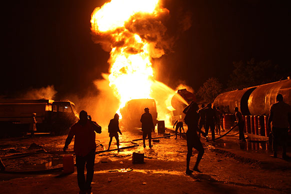 नाइजीरिया के एक पेट्रोल डिपो में लगी आग को बुझाते दमकलकर्मी।