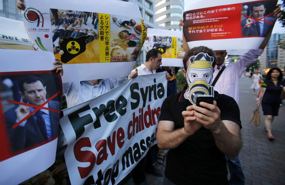 टोक्यो में सीरियाई राष्ट्रपति बशर अल असद के खिलाफ प्रदर्शन करते लोग।