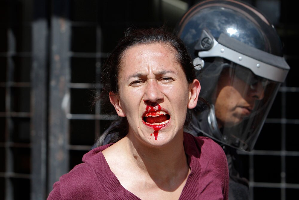 मेक्सिको सिटी में मार्च के दौरान घायल प्रदर्शनकारी को ले जाती पुलिस।