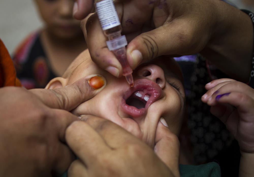 पाकिस्तान के रावलपिंडी में हेल्थ कार्यकर्ता बच्चे को पोलिया की दवा पिलाते हुए।