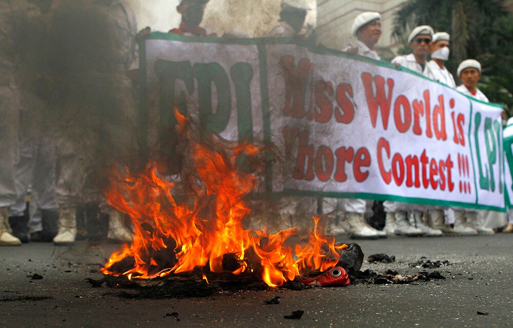इंडोनेशिया के जकार्ता में मिस वर्ल्ड प्रतियोगिता के विरोध में बैनर जलाते लोग।