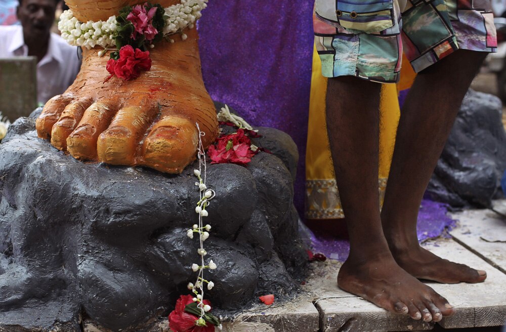 मुंबई में गणेश चतुर्थी पर्व के मद्देनजर भगवान गणेश की विशाल मूर्ति के निकट खड़ा एक श्रद्धालु।