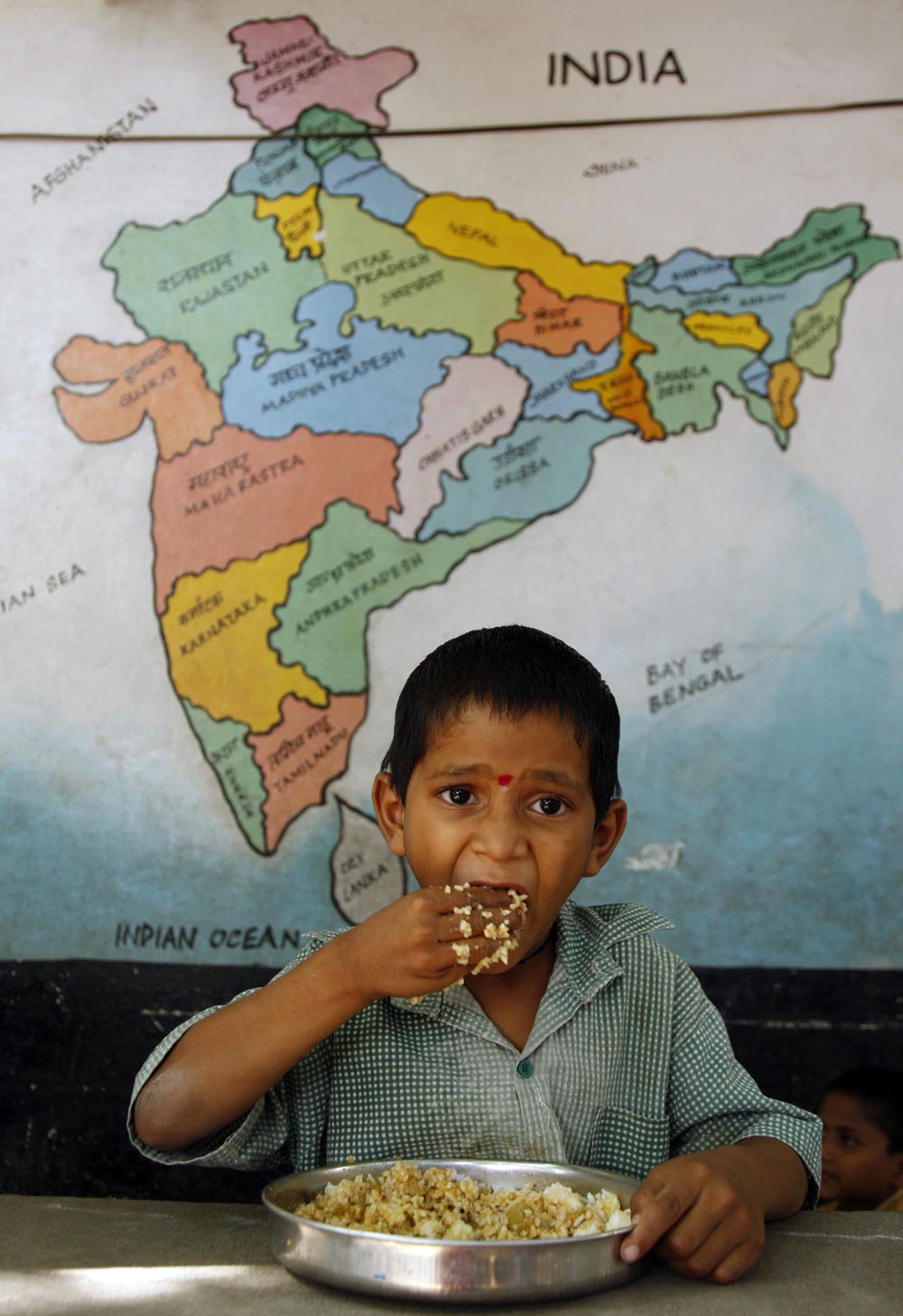 हैदराबाद के एक सरकारी स्‍कूल में मध्‍याहन भोजन को ग्रहण करता हुए एक नन्‍हा छात्र।