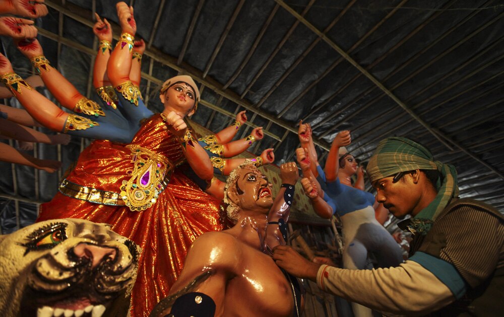 नई दिल्ली में दुर्गा पूजा की प्रतिमा को रंगता एक चित्रकार।