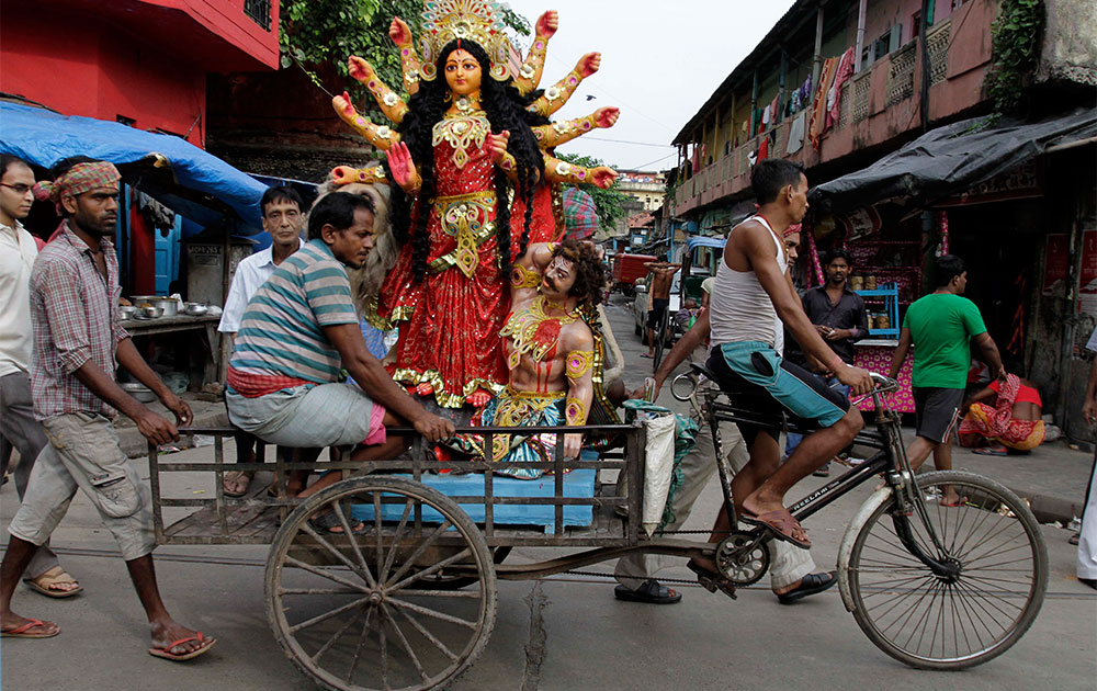 कोलकाता में एक रिक्शा चालक मां दुर्गा की प्रतिमा को ले जाता हुआ।