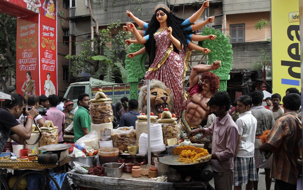 कोलकाता में दुर्गा पूजा के मौके पर विशाल प्रतिमा को स्थापित करते श्रद्धालु।