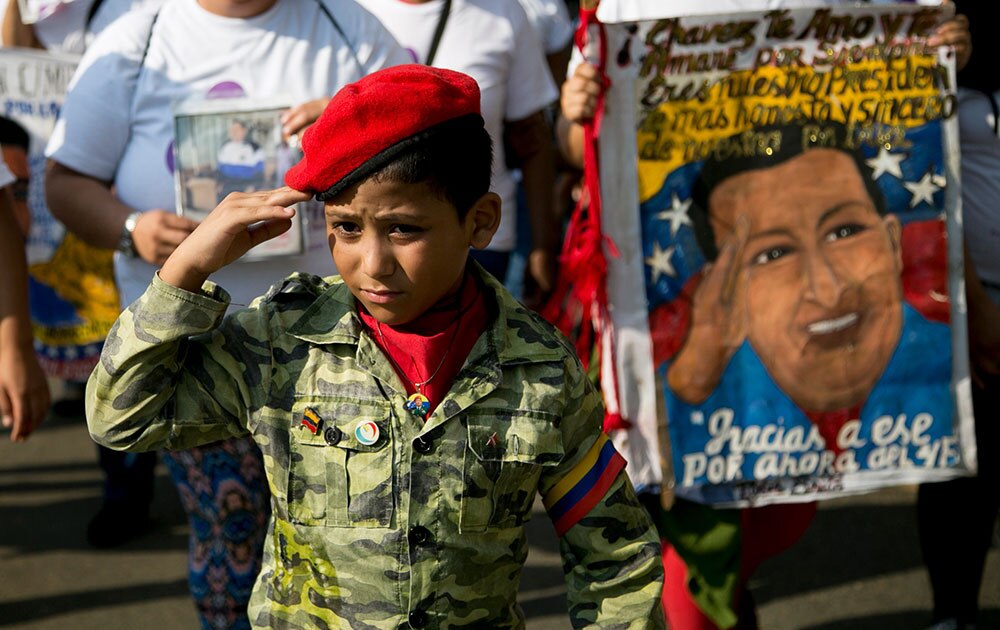वेनेजुएला के पूर्व राष्ट्रपति ह्यूगो चावेज की पुण्यतिथि पर उनकी तस्वीर के साथ एक लड़का।