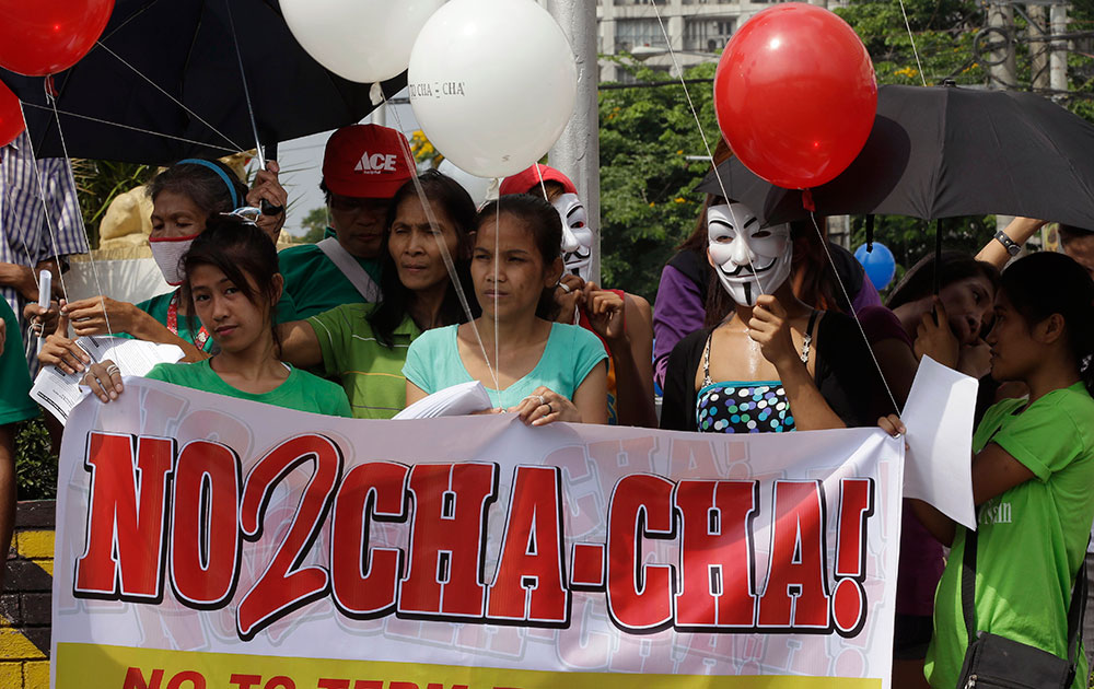 मनीला के उत्तर-पूर्व स्थित क्यूजॉन सिटी में आयोजित रैली में बैनर और गुब्बारे के साथ फिलीपींस में संविधान में बदलाव के खिलाफ प्रदर्शन करते लोग।