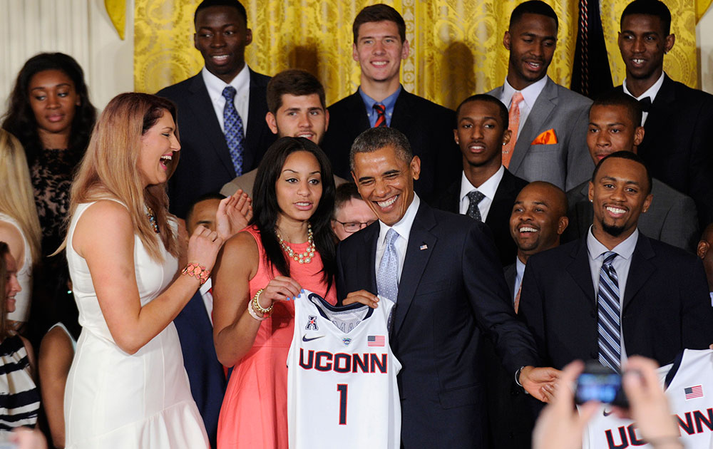 वाशिंगटन के व्‍हाइट हाऊस में एक कार्यक्रम के दौरान एनसीएए चैंपियन यूकॉन हस्‍कीज के पुरुष और महिला बास्‍केटबॉल टीमों के साथ मुस्‍कुराते हुए अमेरिकी राष्‍ट्रपति बराक ओबामा।