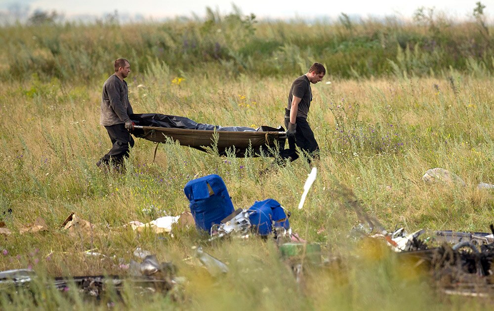 पूर्वी यूक्रेन में मलेशियाई विमान के घटनास्थल से एक मृतक के शव को ले जाता बचावकर्मी। 