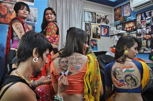 अहमदाबाद में गरबे के लिए अपनी पीठ पर PM नरेंद्र मोदी और अमेरिकी राष्ट्रपति बराक ओबामा की तस्वीरें बनवाती युवतियां।