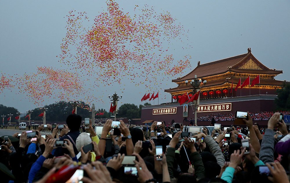 एक समारोह में चीन में बीजिंग के लोग अपने स्मार्टफोन से उस तस्वीर को कैप्चर कर रहे हैं जिसमें बैलून आसमान में छोड़ा जा रहा है। 