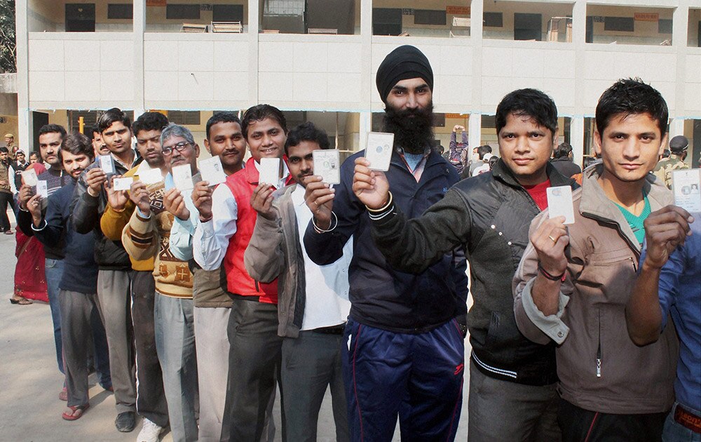 नई दिल्ली के पुल प्रह्लादपुर में दिल्ली विधानसभा चुनाव के मद्देनजर वोट डालने से पहले कतार में खड़े मतदाता अपना पहचान पत्र दिखाते हुए।