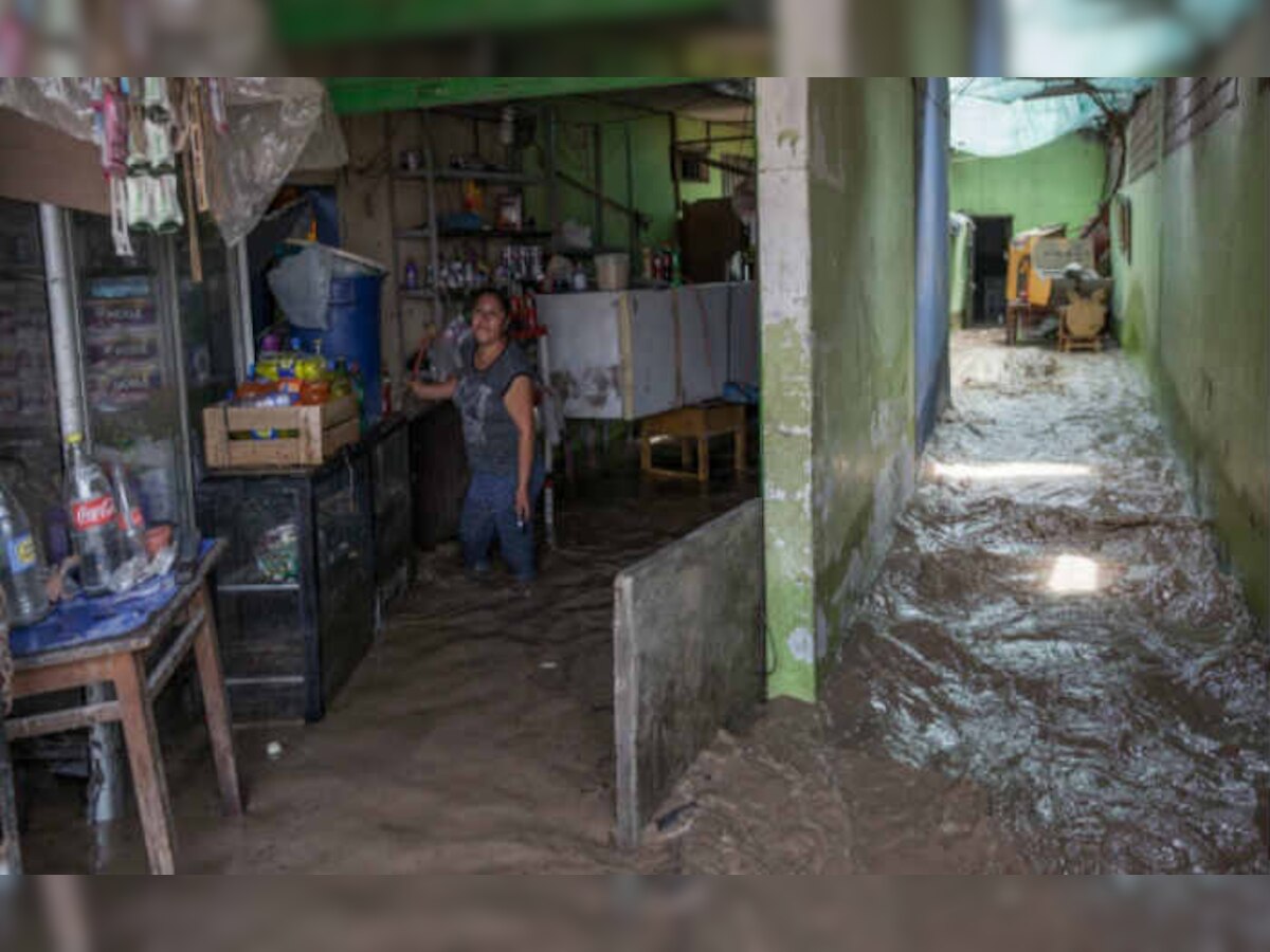 पेरू की राजधानी लीमा में बाढ़ से प्रभावित अपने घर में काम करती हुई। (एपी फोटो)