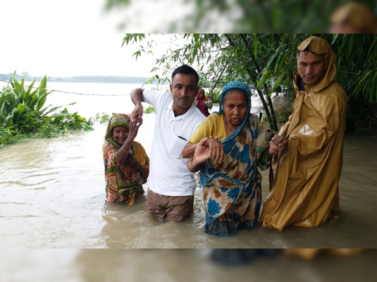 असम के कोकराझार में बाढ़ में फंसे लोगो को सुरक्षित स्थानों पर ले जाते सीआरपीएफ के जवान. (PHOTO : CRPF‏/Twitter)