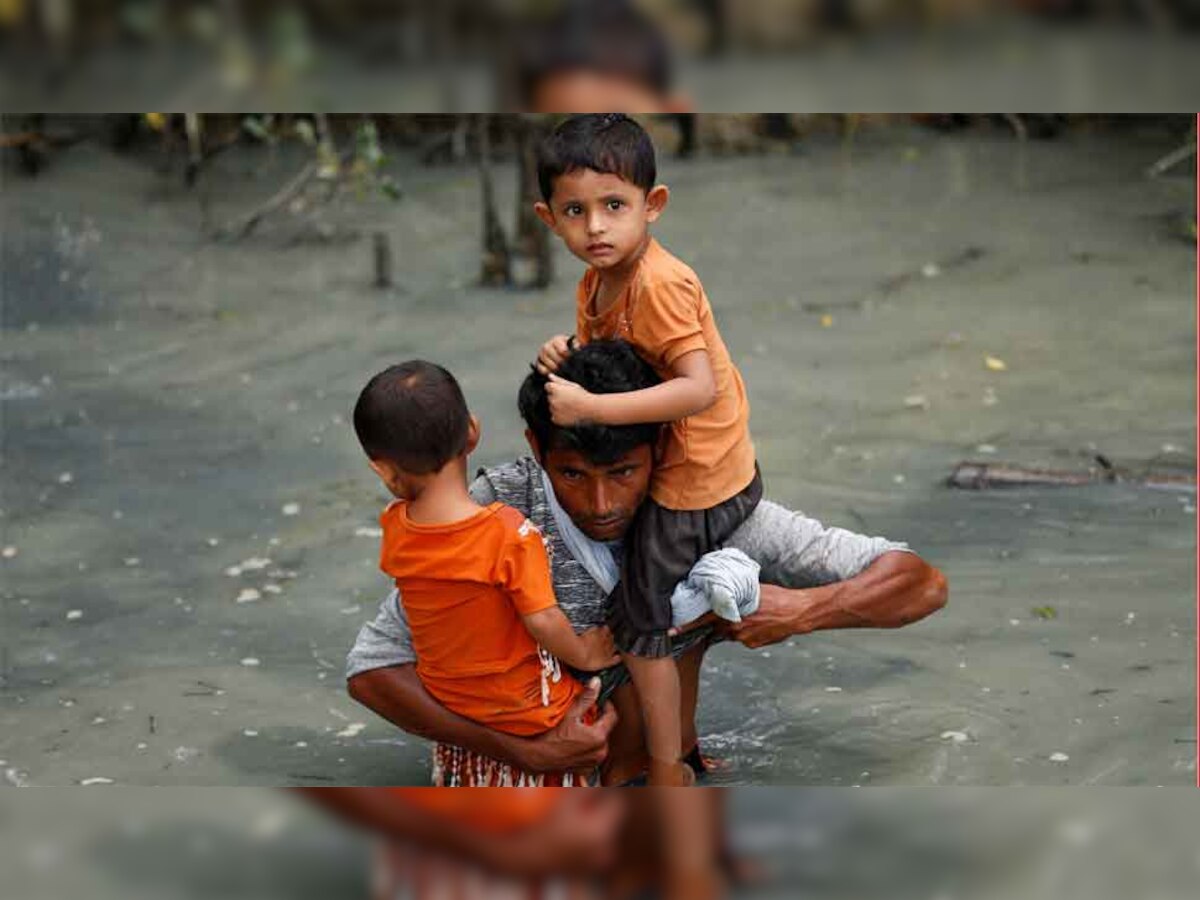 नाव से नाफ नदी द्वारा सीमा पार करने के बाद बांग्लादेश के तेकनफ में एक शरणार्थी अपने बच्चों को लेकर पानी में चलता हुआ. (Reuters/8 Sep, 2017)
