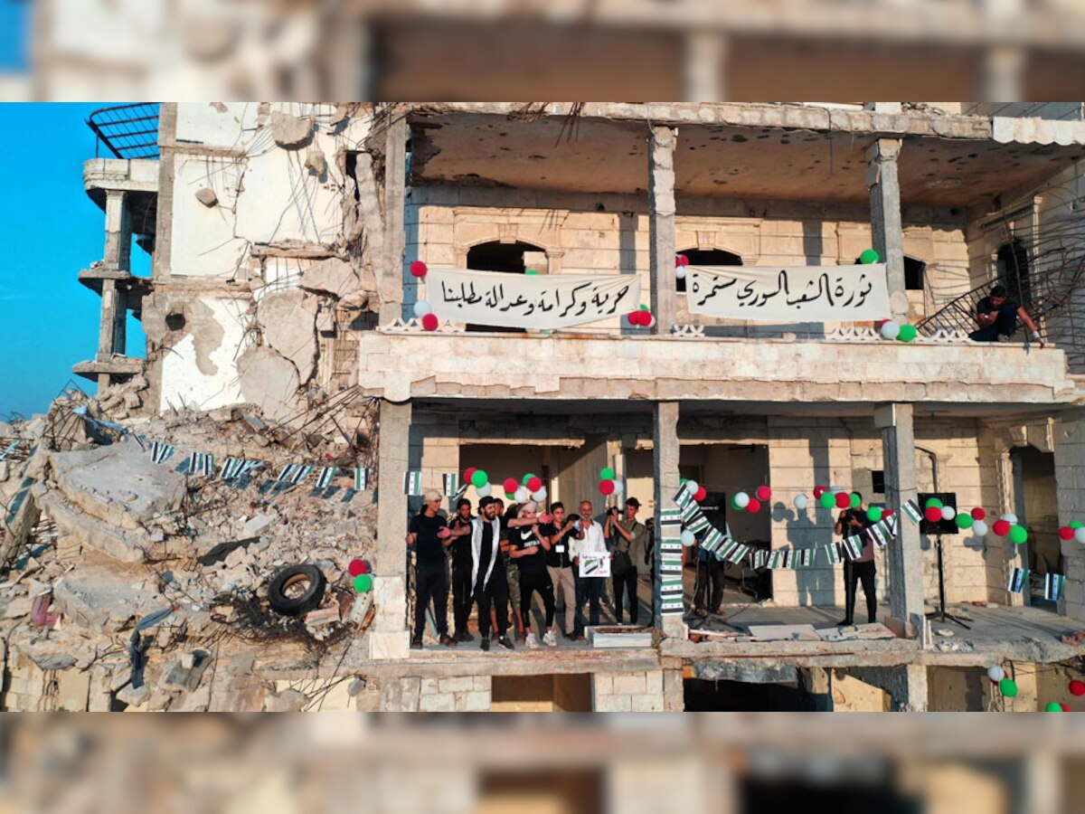 सीरिया में गृहयुद्ध से बर्बाद इमारत में खड़े लोग (फाइल फोटो)