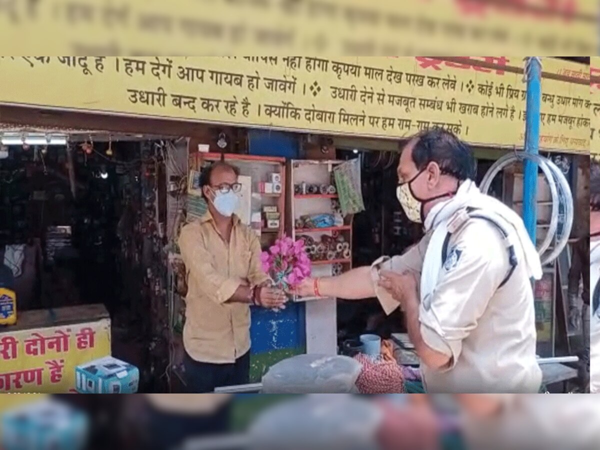 हाथों में फूल लेकर दुकानदारों को समझा रहे पुलिस जवान 