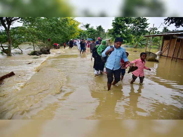 असम के होजाई जिले में गाँव में बाढ़ का पानी घुसने के बाद सुरक्षित स्थान पर जाते हुए लोग 