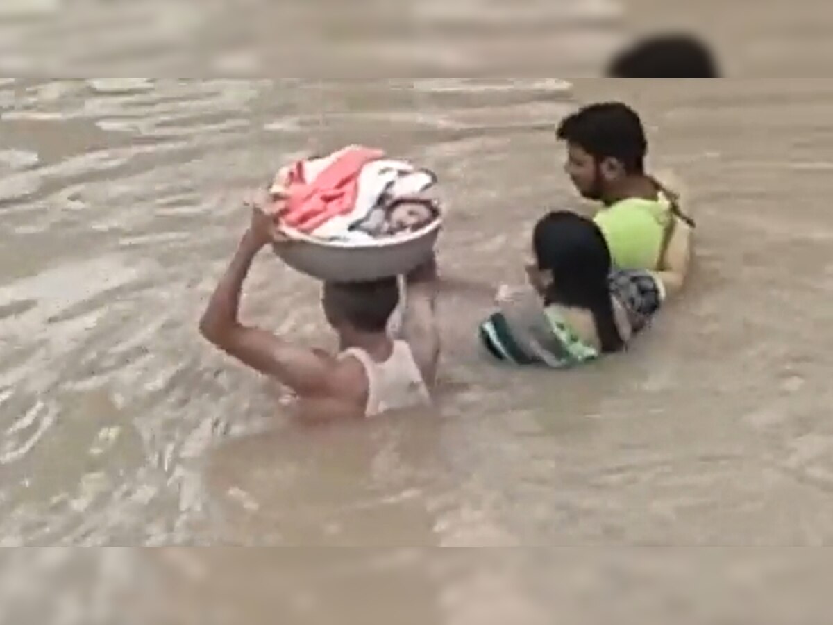 बच्चे को सिर पर लेकर बाढ़ के गहरे पानी में घुस गया ये शख्स, देखें चौंका देने वाला Shocking Video