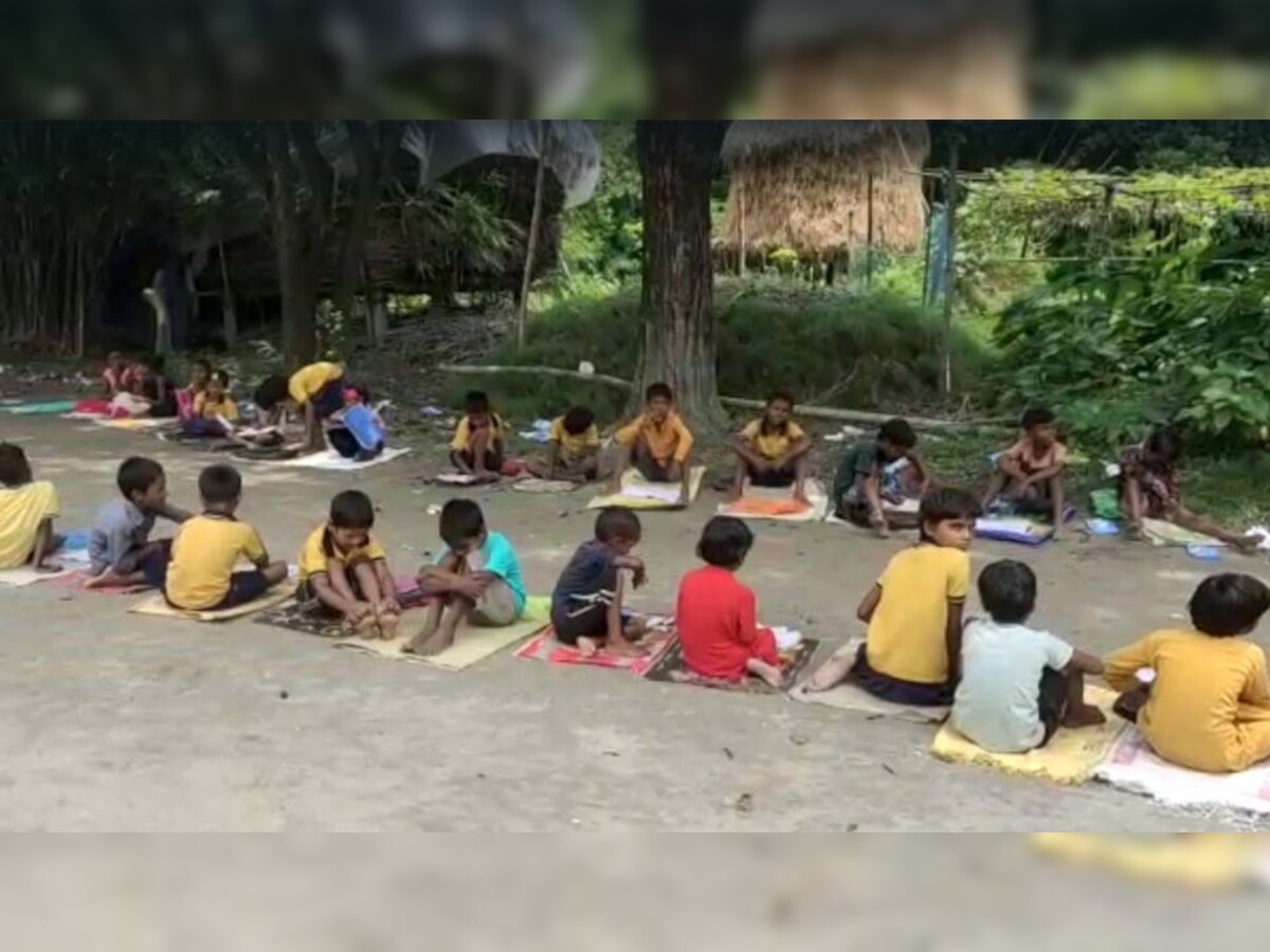 असम के एक सरकारी स्कूल के बाहर खुले आसमान के नीचे पढाई करते छात्र 
